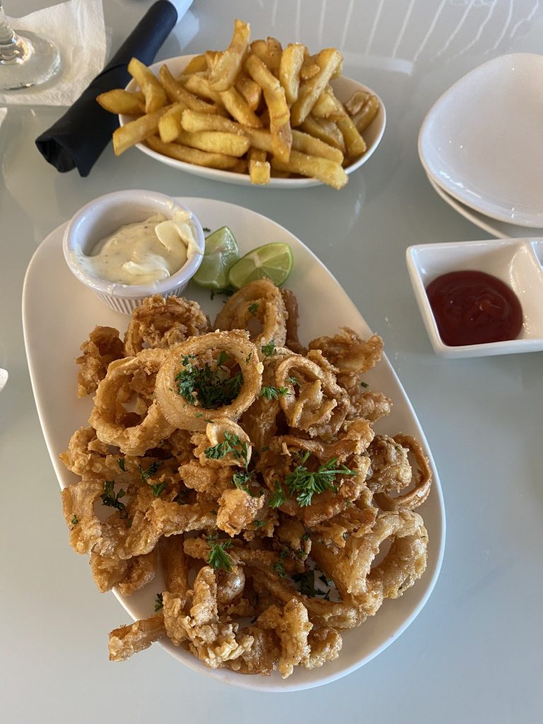 Picture of fried calamari with lime and white sauce on the side and some truffle fries