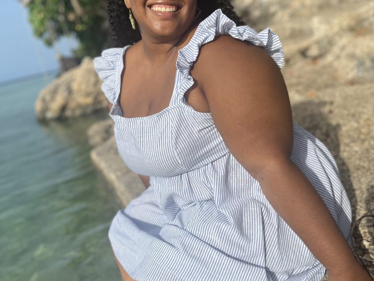 Samantha sitting smiling by water in a blue dress